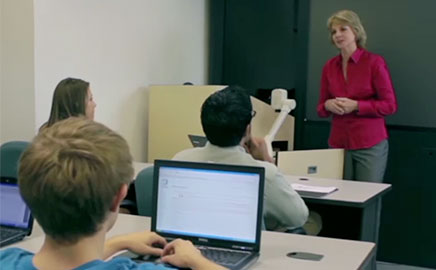 Instructor teaching a class of students working on laptops