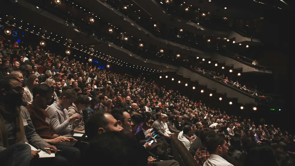 A packed lecture auditorium seen from the balcony