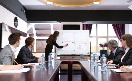 Presenter at a whiteboard leading a meeting in a corporate boardroom