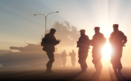 Soldiers silhouetted at dawn beside armoured vehicles