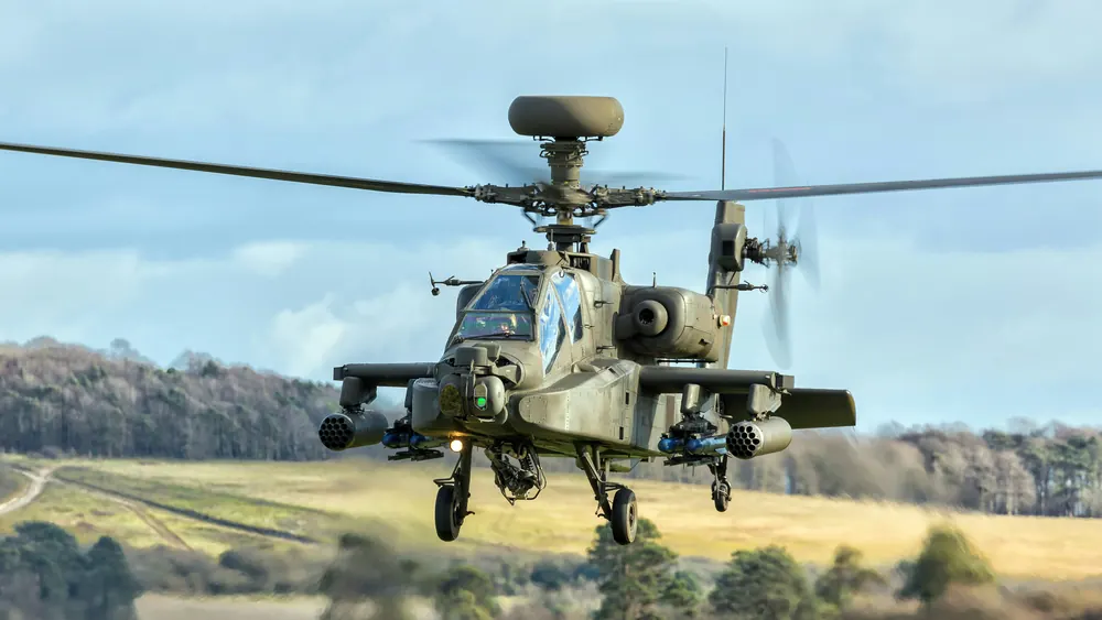 An Apache attack helicopter low over open ground